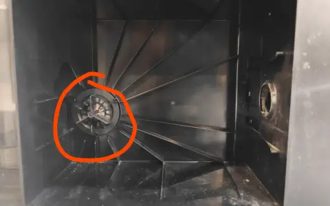 Der Staubbehälter eines Ecovacs Saugroboters, bereit zum Wechseln des Staubbeutels. Der Lüfter ist mit Staub bedeckt.