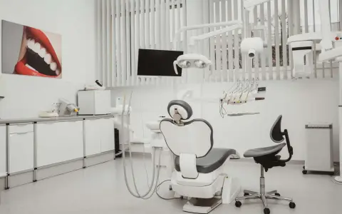 Nowoczesny gabinet stomatologiczny z fotelem, unitem i obrazem uśmiechu.