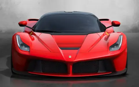 Przód czerwonego LaFerrari z czarnym dachem i przyciemnianymi szybami, błyszczący na tle szarej ściany.
