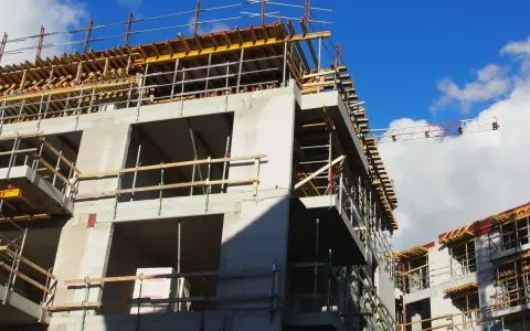 Rohbau eines Mehrfamilienhauses im Rahmen der Entwicklung von urbane gebiete. Gerüste und Betonstrukturen unter blauem Himmel.