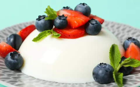 Szybkie ciasto z 4 składników: panna cotta z jagodami i truskawkami, ozdobiona miętą.