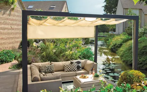 Nowoczesna pergola z wysuwanym daszkiem to idealny sposób, jak osłonić taras od wiatru i słońca. Wygodny narożnik i stolik zachęcają do relaksu.