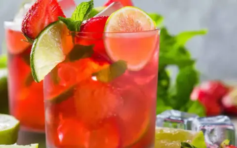Två glas med en uppfriskande strawberry mojito, garnerade med jordgubbar, lime och mynta. Perfekt för en varm sommardag.