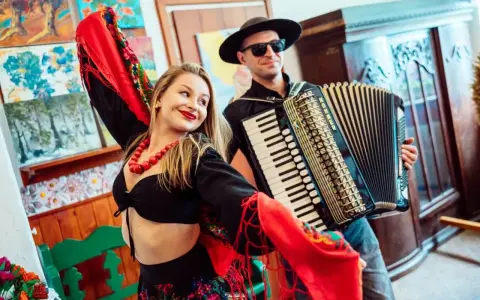 Zespół góralski disco polo w akcji! Wokalistka w barwnym stroju i akordeonista tworzą radosną atmosferę.