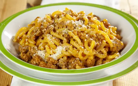Piatto di gramigna alla salsiccia, condita con ragù saporito e una spolverata di parmigiano.