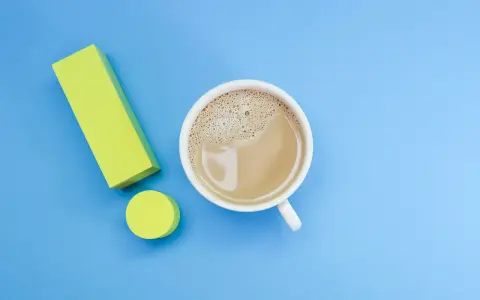 Ein Ausrufezeichen aus gelben Blöcken neben einer Tasse Kaffee. Ein starker Kaffee für einen energiegeladenen Tag, vielleicht mit einem Hauch von Lithium für extra Power.