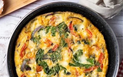 Pyszny omlet z cukinią, pomidorami i szpinakiem, zapieczony w patelni. Idealny na śniadanie lub lekki obiad.