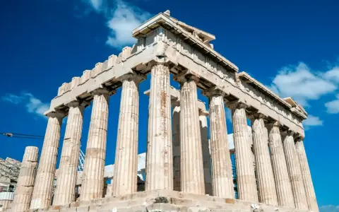 Le Parthénon, temple d'Athéna, se dresse majestueusement sous un ciel bleu éclatant, ses colonnes doriques témoignant de la grandeur de l'Acropole d'Athènes.