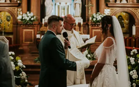 Para Młoda podczas uroczystości ślubu konkordatowego w kościele. Pan Młody w garniturze, Panna Młoda w sukni ślubnej.