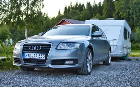 Grauer Audi A6 F4 Kombi mit Wohnwagen im Hintergrund, bereit für den Urlaub.
