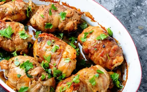 Involtini di carne dorati e succulenti, guarniti con prezzemolo fresco, cotti in una teglia bianca.