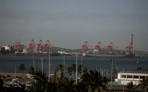 Port w Durban, RPA, z czerwonymi dźwigami portowymi i statkami towarowymi na tle wzgórz. Na pierwszym planie widać maszty jachtów.