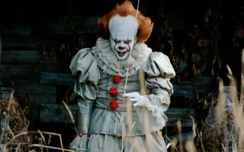 Przerażający klaun Pennywise, znany z horrorów Netflix, wychodzi z mroku.