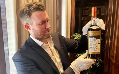 Mężczyzna w białych rękawiczkach prezentuje butelkę The Macallan 60 Year Old, jedną z najdroższych whisky świata.