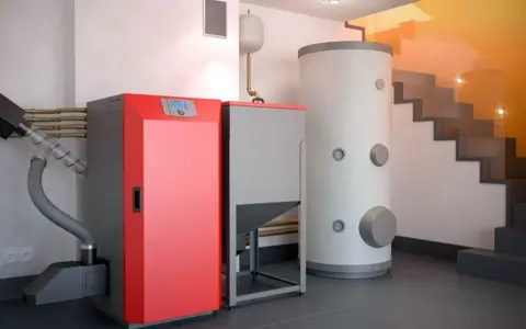 Instalación moderna para cambiar caldera de gas por pellets. Caldera roja, depósito de pellets y acumulador de agua.