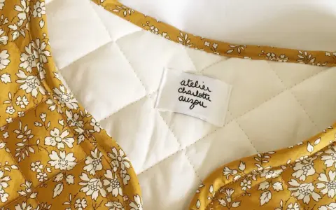 Détail d'une veste matelassée femme avec un tissu fleuri jaune moutarde. Un patron gratuit pour créer ce modèle est disponible.