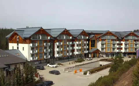 Widok z kamer w Bukowinie Tatrzańskiej na nowoczesny hotel z drewnianymi elementami i parkingiem.