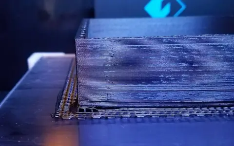 Drukarka 3D tworzy obiekt z czarnego materiału PEEK, warstwa po warstwie.