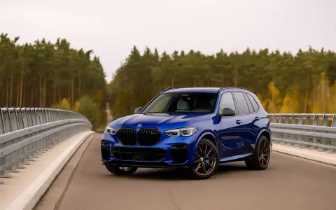 Niebieskie BMW X5 na moście, otoczone jesiennym lasem. Idealne do rozkodowanie vin bmw.