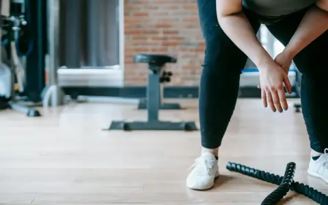 Zmęczona po treningu, z rękami opuszczonymi w geście poddania. Złe samopoczucie po treningu dopadło ją w siłowni.