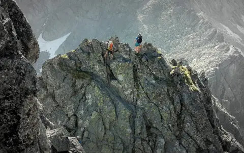 Dwóch alpinistów pokonuje skalisty grzbiet. Jeden z nich zjeżdża na linie, drugi czeka na szczycie. To trudna droga Martina na Gerlach.