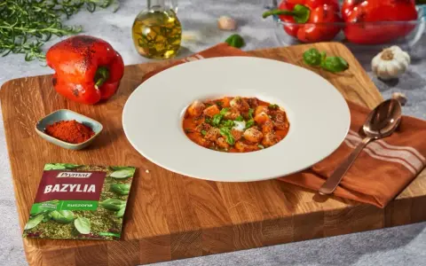 Aksamitny krem z pieczonej papryki z grzankami i bazylią. Obok składniki: papryka, oliwa, czosnek, przyprawy.