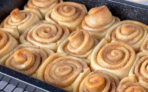 Frisch gebackene Zimtschnecken im Blech, bereit für das Zimtschnecken Rezept. Goldbraun und duftend, ein Genuss!
