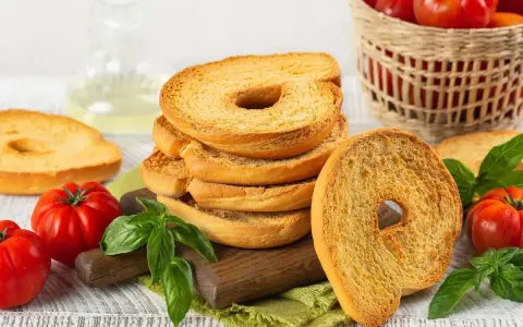 Fette dorate di pane tipico pugliese, con pomodori freschi e basilico, pronte per essere gustate.