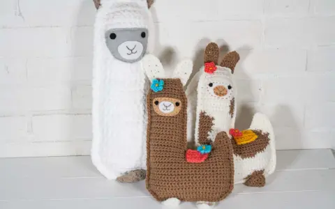 Un grupo de adorables llamas amigurumi, hechas a mano con lana, posan juntas.