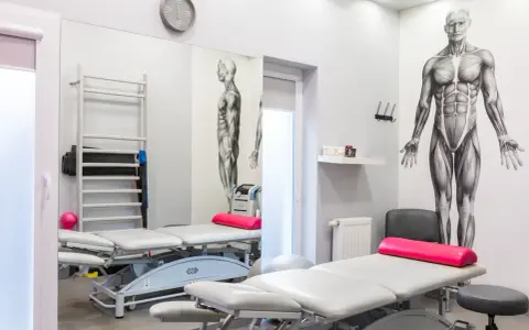 Gabinet rehabilitacyjny z leżankami, drabinką, piłką i aparaturą, w tym magnetronik na kolano.