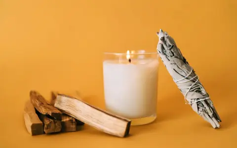 Palosanto, vela encendida y manojo de salvia. Prepara tu espacio para como quemar palo santo y purificar el ambiente.