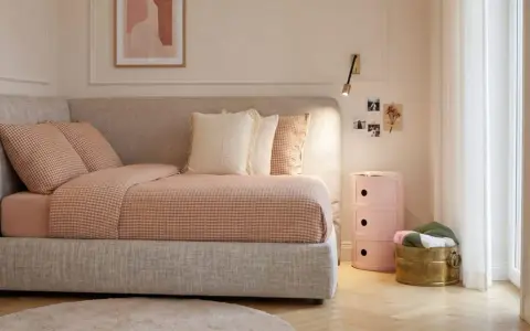 Camera da letto ragazza aesthetic: letto accogliente con biancheria a quadretti, cuscini morbidi, comodino rosa e decorazioni murali.