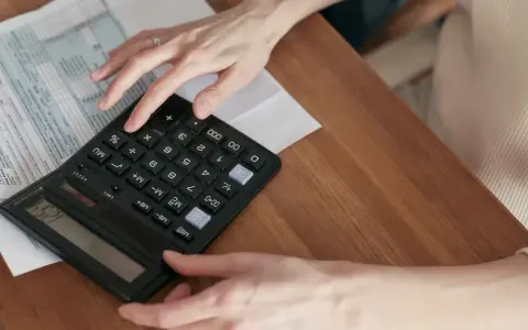 Manos calculando el total de suplidos en un formulario fiscal.