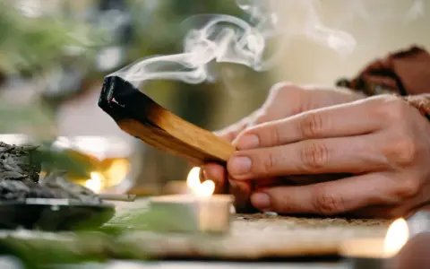 Dym z palo santo unosi się nad płonącą świecą. Zastanawiasz się, palo santo dlaczego nie używać?