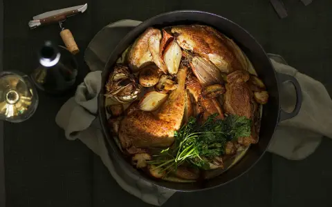 Ein Brathähnchen mit Zwiebeln und Kräutern, bereit zum Genuss. Dazu ein Glas Wein, der den Riesling Geschmack unterstreicht.