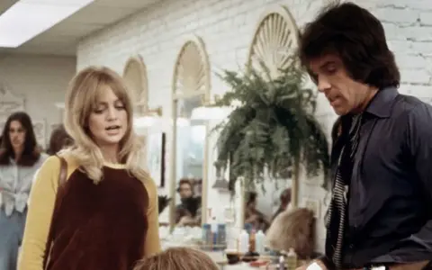 Goldie Hawn och Warren Beatty i en scen från en film. Hon har blont hår och en gul och brun tröja. Han har mörkt hår och en mörk skjorta.