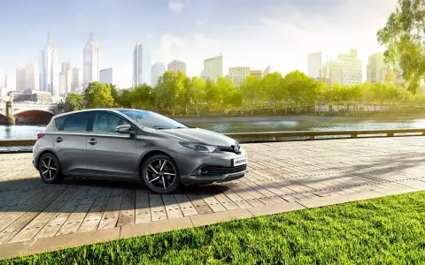 Szary Toyota Auris Hybrid na drewnianym pomoście, z miastem w tle. Jaki olej do tego modelu?