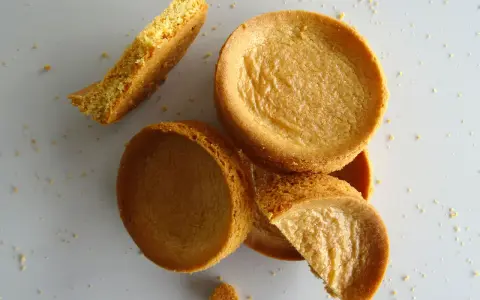 Des morceaux de sablé breton moelleux, certains entiers, d'autres brisés, éparpillés sur un fond clair.