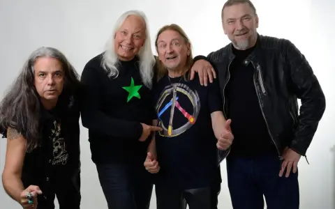 Czterech mężczyzn, TSA Dream Team, pozuje do zdjęcia. Dwóch z nich ma długie włosy, jeden w czarnej koszulce z zieloną gwiazdą, drugi w koszulce z symbolem pokoju.