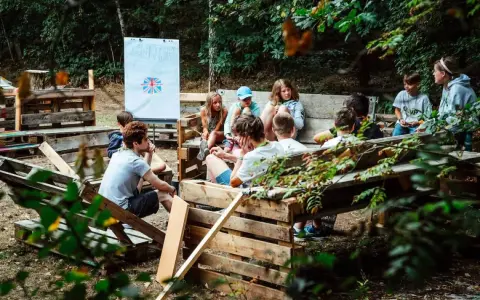 Kinder lernen im Freien beim englisch camp. Eine Tafel mit der britischen Flagge steht im Hintergrund.