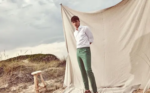 Un uomo con camicia bianca e pantalone verde, un look perfetto per l'estate. Scopri come abbinare un pantalone verde per un outfit fresco e alla moda.