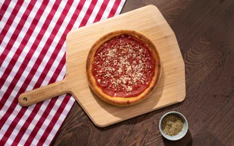Pizza sur planche en bois, avec une nappe à carreaux rouges et blancs. La proportion levain farine eau est parfaite pour cette croûte dorée.
