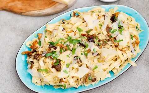Tagliatelle z grzybami, posypane parmezanem i natką pietruszki. Pyszny przepis na makaron z leśnymi grzybami.
