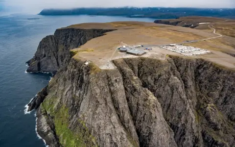 Majestatyczne klify na Nord Kapp, z widokiem na ocean i budynkami turystycznymi.