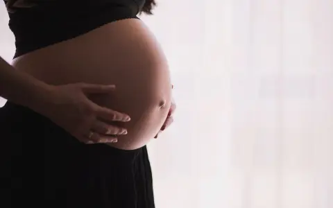 Gravid mage med händer som varsamt håller om den. Kanske funderar hon på proteinpulver gravid för att ge extra näring.