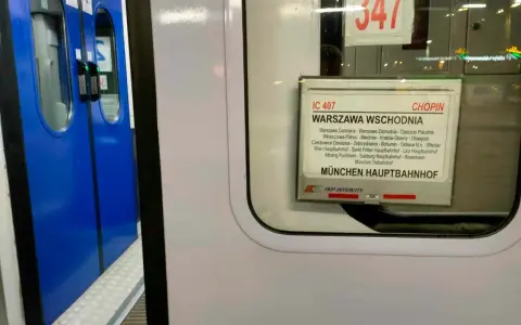Tabliczka z rozkładem jazdy pociągu IC 407 Chopin na tle niebieskich drzwi pociągu.