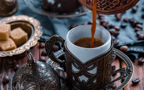 Heißer Mokka wird in eine verzierte Tasse gegossen. Der Unterschied zwischen Mokka und Espresso liegt in der Zubereitung und Intensität.