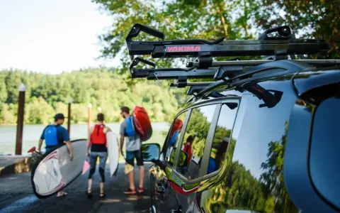 Ludzie przygotowują się do wodnej przygody, transport kajaka i desek SUP do jeziora.