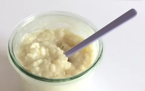 Budino cremoso, profumato alla vaniglia, come quello della ricetta della nonna, pronto per essere gustato con un cucchiaino viola.