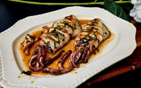 Calamar a la plancha, jugoso y tierno, bañado en una salsa dorada con hierbas. ¡Perfecto para aprender como hacer calamar a la plancha!